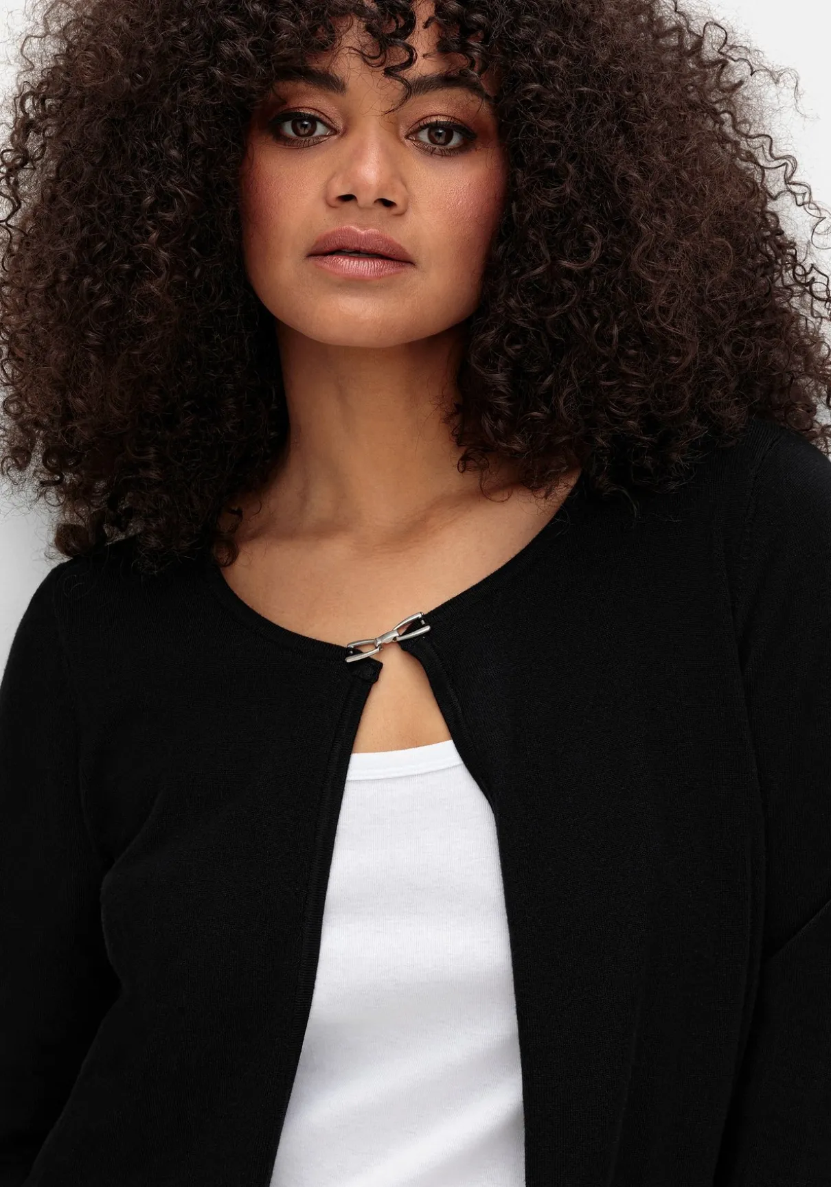 Kurze Strickjacke mit Zierspange am Ausschnitt